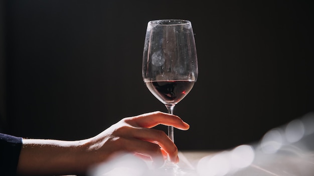 Фото Пара рук, держащих стакан красного вина, изолированный на черном фоне