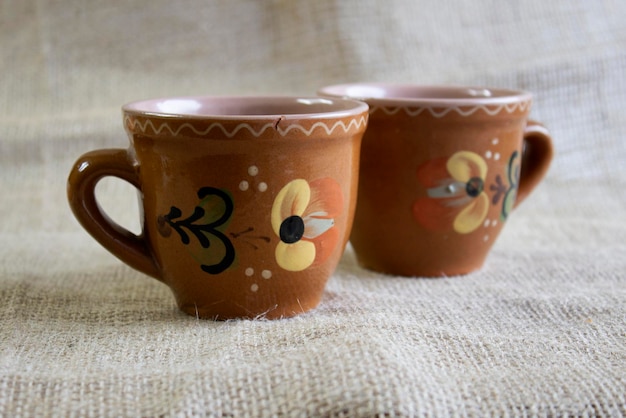 Photo set of old clay mugs on linen cloth selected focus