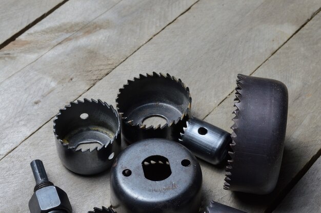 A set of old crowns for drilling a tree lies on a plank, wooden background. close-up.