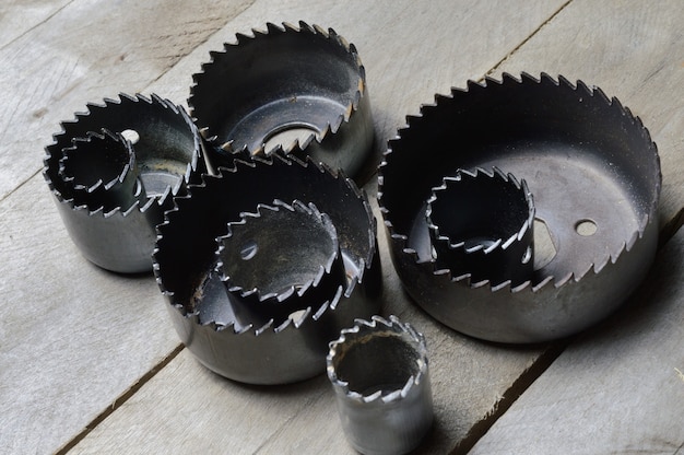 a set of old crowns for drilling a tree lies on a plank, wooden background. close-up.