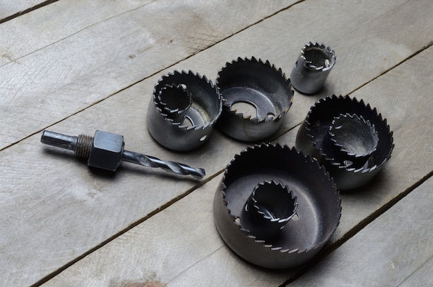 A set of old crowns for drilling a tree lies on a plank, wooden background. close-up.