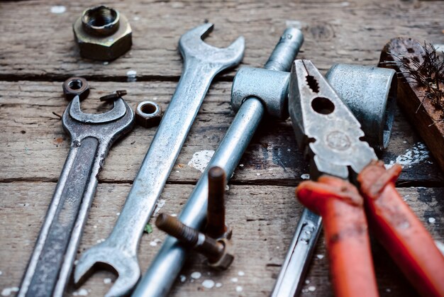 Set old manual tools. Weathered wooden surface lie the old, oily spanners, pliers. Near scattered old rusty nuts.