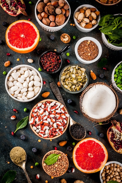 Set of organic healthy diet food, superfoods - beans, legumes, nuts, seeds, greens, fruit and vegetables. Dark blue background copy space top view