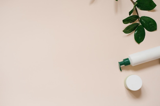 Set of organic SPA cosmetics with green leaves Top view of bottles made of white recyclable plastic on a beige background Packaging design of natural cosmetics for skin care