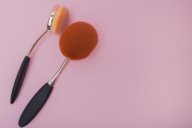 Photo set of oval brushes for makeup on pink background