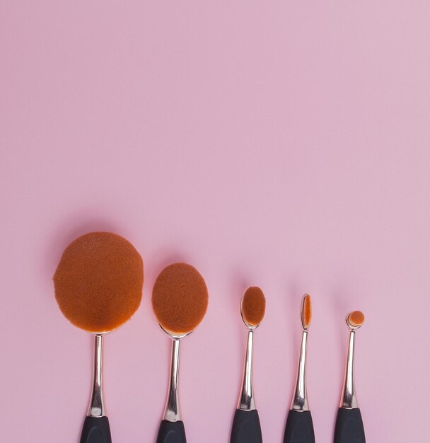 Set of oval brushes for makeup on pink background