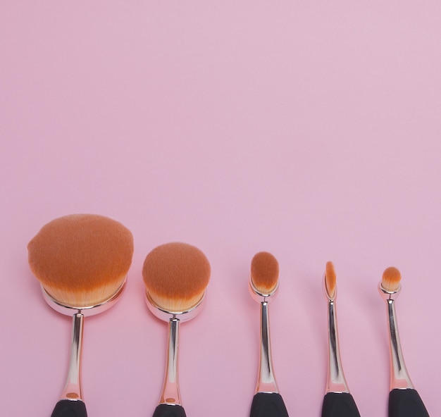 Set of oval brushes for makeup on pink space