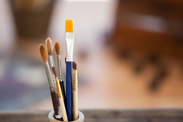 Set of paint brushes in a jar on wooden table