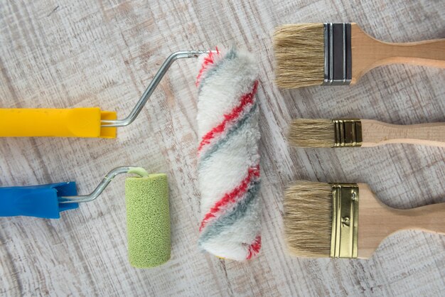 Set of paint brushes and roller on wooden desk. All for repair