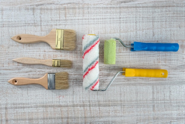 Set of paint brushes and roller on wooden desk. All for repair