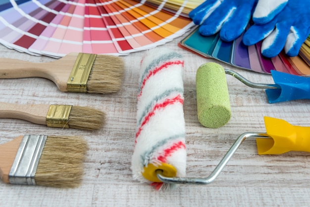 Set of paint brushes and roller on wooden desk