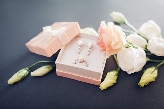 Set of pearl jewellery in gift box with flowers. Silver earrings and ring with pearls as a present