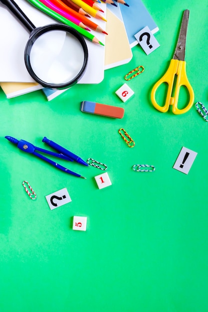 Photo a set of pencils, notebooks, compasses, scissors isrepok on green