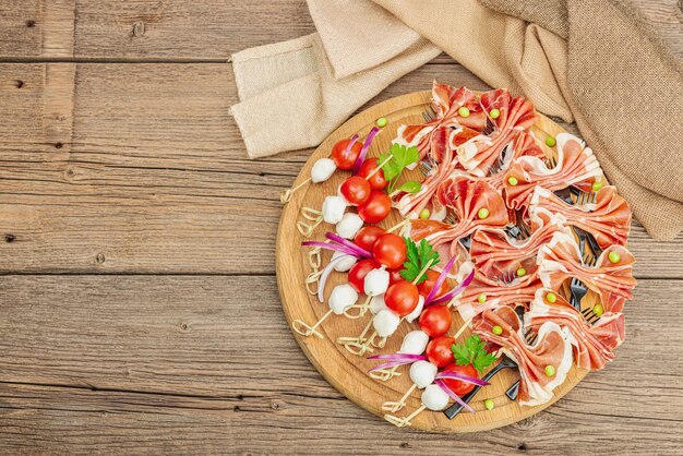 Foto set di snack da picnic su spiedini jamon mozzarella pomodorini piselli verdure fresche stand moderno sfondo in legno vista dall'alto