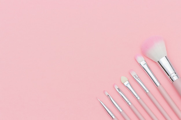 Set of pink makeup brushes on pastel pink background