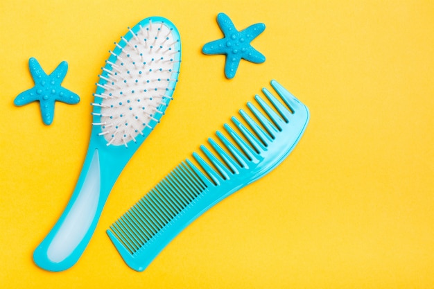 A set of plastic combs and two hairpins in the shape of a starfish on a yellow background. 