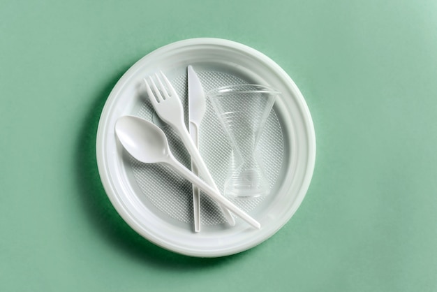 Photo set of plastic disposable tableware on a green background