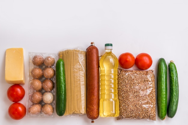 Foto un set di prodotti su uno sfondo bianco. generi alimentari, verdure, burro, uova e salsiccia. pacchetto alimentare