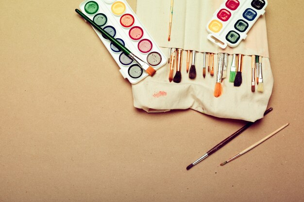 set of professional watercolor artist brushes in a  hand made roll case and watercolor paints close up
