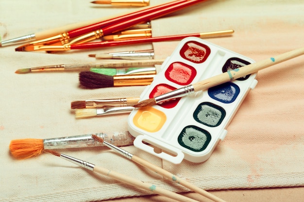 Set of professional watercolor artist brushes in a hand made roll case and watercolor paints close up