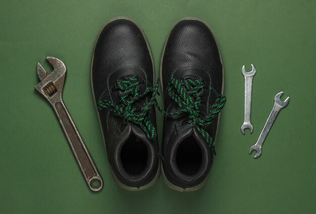 Set of professional work tools and boots on green background. Top view.