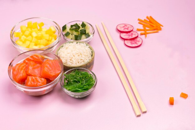 Set of raw vegetables red fish rice soy sauce in glass bowls Hawaiian dish Bamboo chopsticks