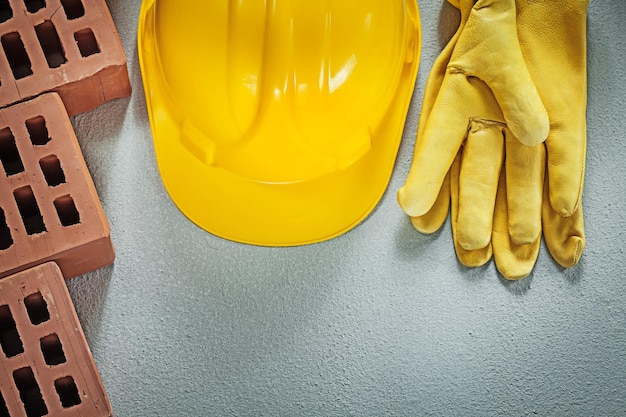 Набор защитных перчаток в каске из красного кирпича на бетонном фоне концепции строительства