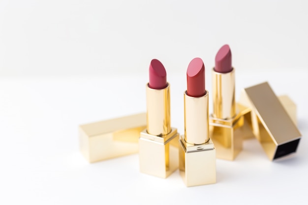 Set of red lipsticks in golden cases on white