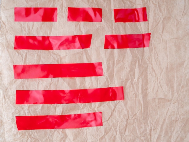 Photo set of red tapes on crumpled brown wrapping paper torn horizontal and different size red sticky tape