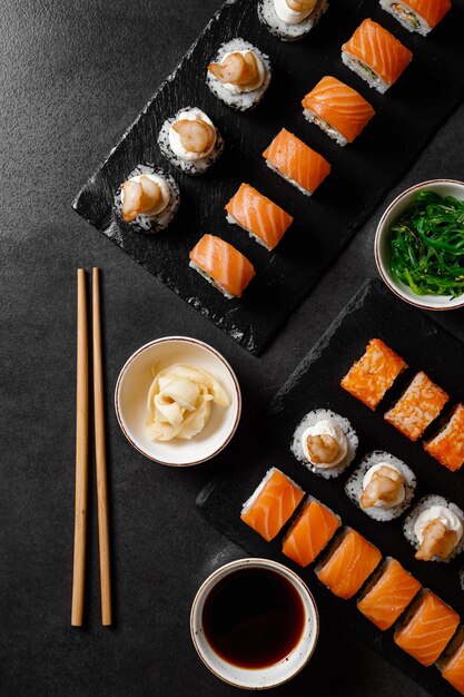 Set of rolls with salmon sauce wasabi hiashi wakame on a dark background