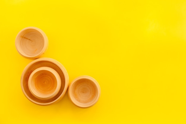 Set of rustic wooden tableware bowls and utensils on yellow