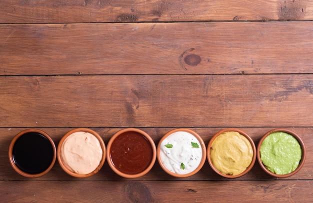 Photo set of sauces in bowl on wooden background