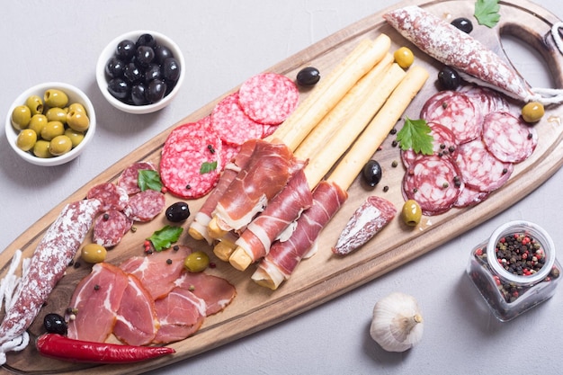 Set of sausages ham salami jamon and olives on wooden board