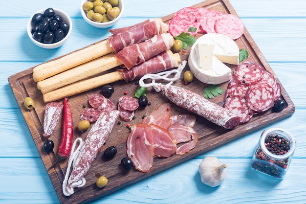 Set of sausages ham salami jamon and olives on wooden board