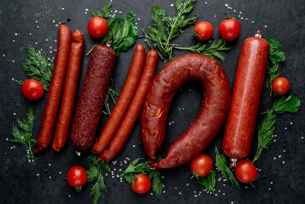 Set of sausages, salami and smoked meats with rosemary and spices on a stone