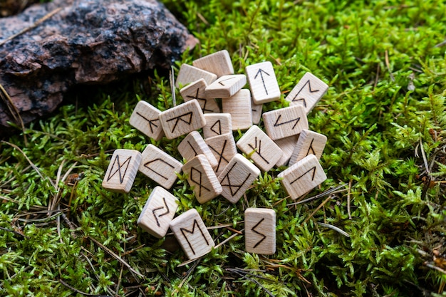 
A set of Scandinavian runes made on wooden dice lies on a natural moss. Fortune telling tool, concept of predicting the future.