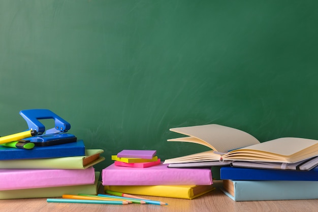 Set of school supplies on table near blackboard