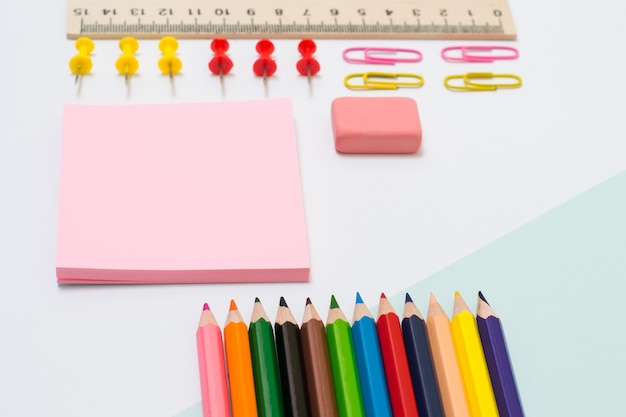 Set of school supplies. Top view close up photo of color pencils, stickers, paper clips and pins, rubber, ruler on white background