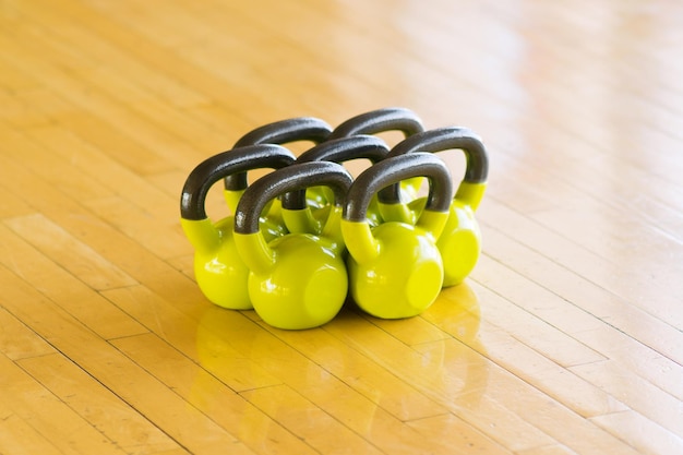 A set of seven yellow dumbbells with black handles lying on the parquet floor Toned