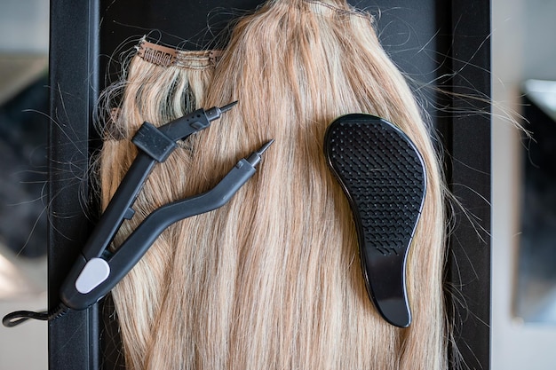 A set of several hair extension tools for a blonde woman in a\
beauty salon pliers and micro tubes