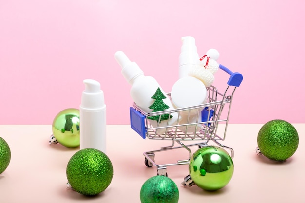 A set of skin care cosmetics in a shopping cart and Christmas tree decorations Moisturizing face cream with Christmas accessories Buying Christmas gifts Winter skin care concept