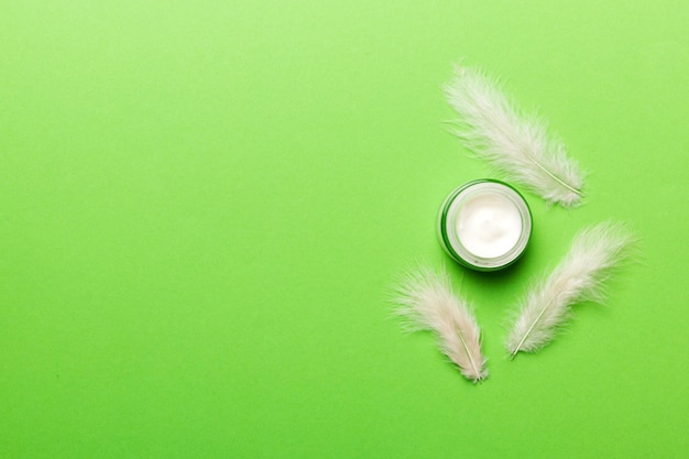 Set of skin care serums on pink pastel background with ostrich feathers Spa cosmetic product cream jar branding mock up top view with copy space