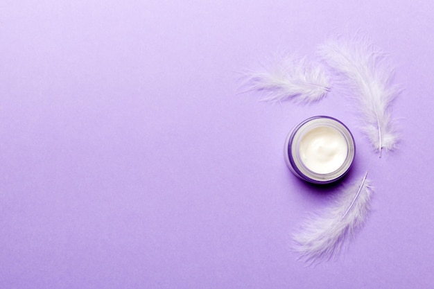 Set of skin care serums on pink pastel background with ostrich feathers Spa cosmetic product cream jar branding mock up top view with copy space