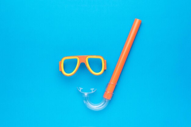 Photo a set of snorkel and mask for scuba diving on a blue background an accessory for scuba diving flat lay
