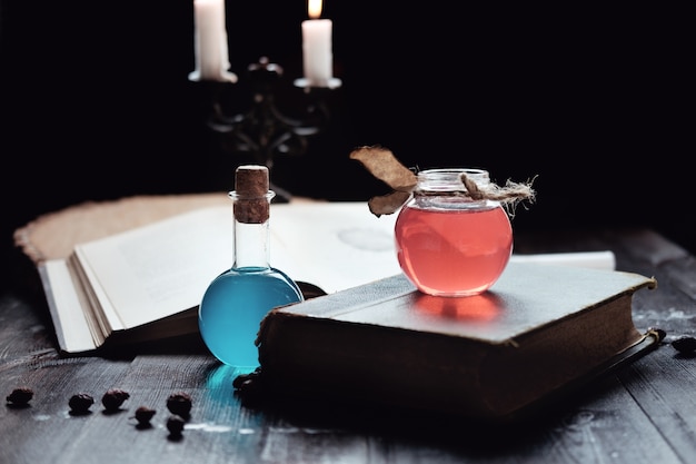 Set of sorcery book, magic potions and candles on table