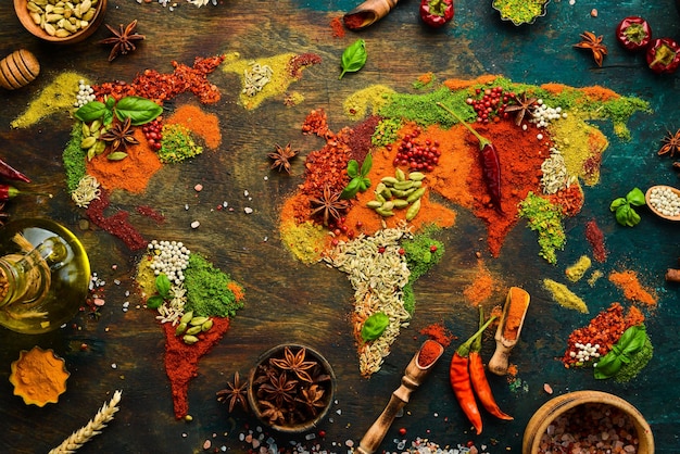 Foto set di spezie ed erbe aromatiche cucina indiana mappa del mondo pepe sale paprika basilico curcuma su una tavola di legno nera vista dall'alto spazio libero per la copia