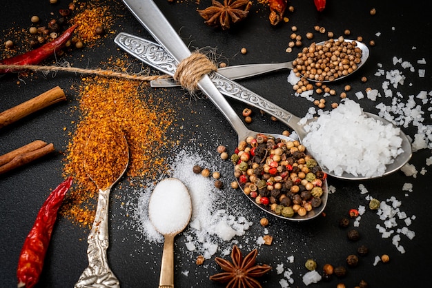 A set of spices and herbs with spoon and copy space on black background