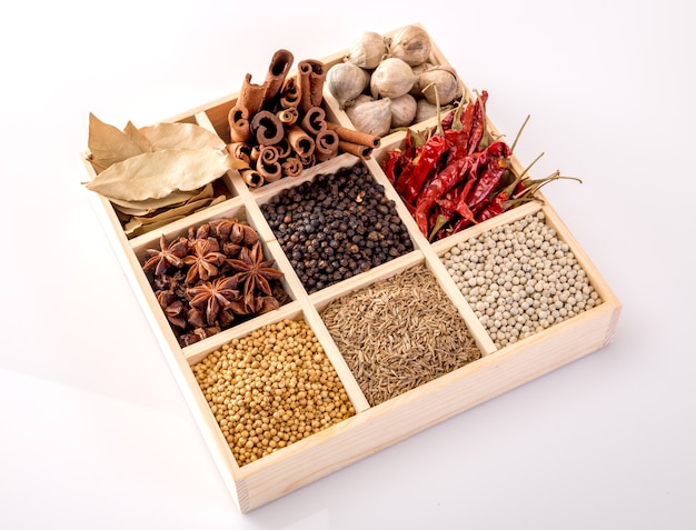 Set of spices (pepper, white pepper, black pepper, anise, caraway,) in a wooden box.