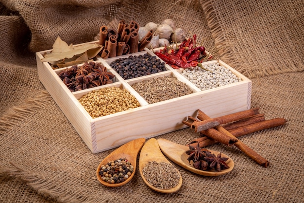 Set of spices (pepper, white pepper, black pepper, anise, caraway,) in a wooden box.