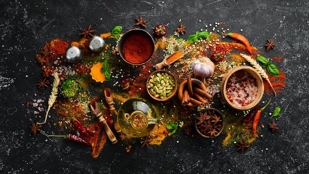 Set of spices and seasonings on a black stone background. Top view.